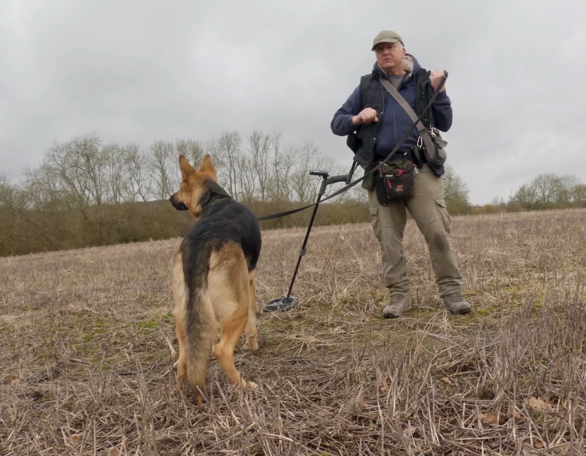 Man in a field training a German Shepherd